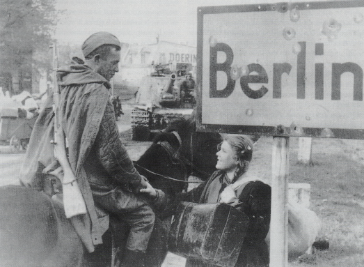 Soldado de caballería soviético hablando con una chica rusa que regresa al hogar tras realizar trabajos forzados en Alemania. En segundo plano un cañón de asalto SU-122