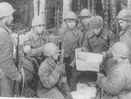 Un comandante de un pelotón de infantería leyendo un periódico a sus hombres. Estos van armados con el fusil SVT-40