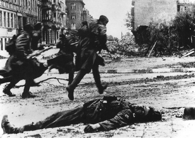 Infantería soviética luchando en las calles de Berlín. En el suelo un soldado alemán muerto. Abril de 1945